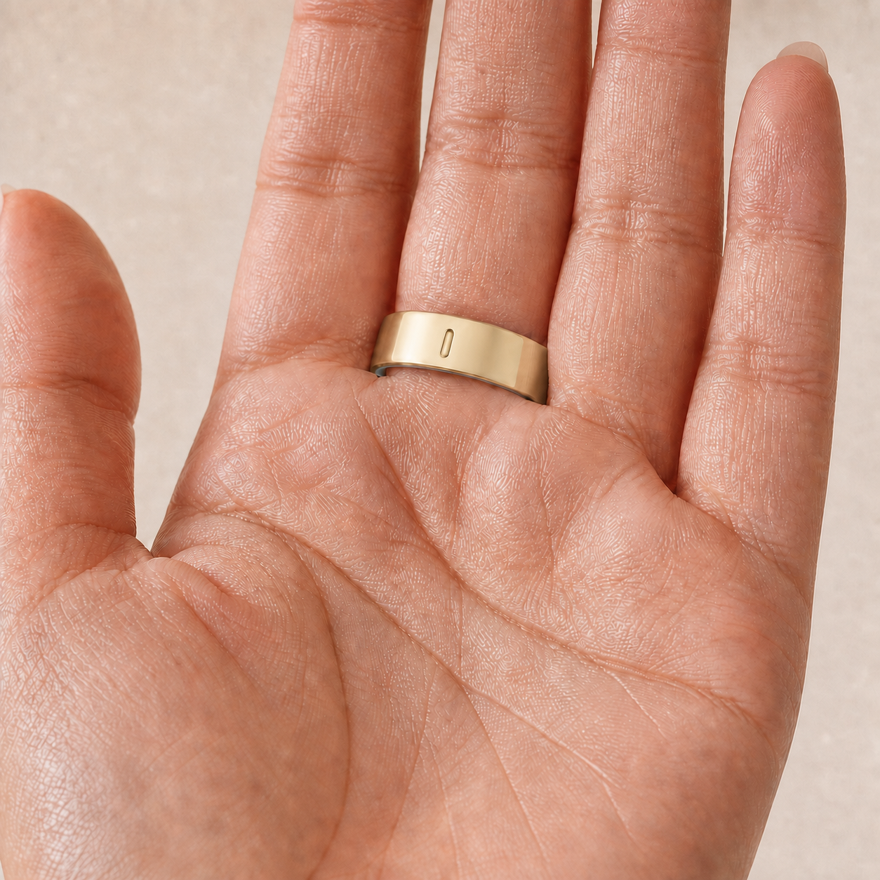 Palm view of the Oura Ring 5 Gold Tone cover with the indicator opening facing the palm