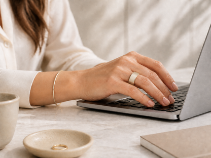 Oura Ring 5 Gold Tone cover worn while typing with the smooth outer side facing up