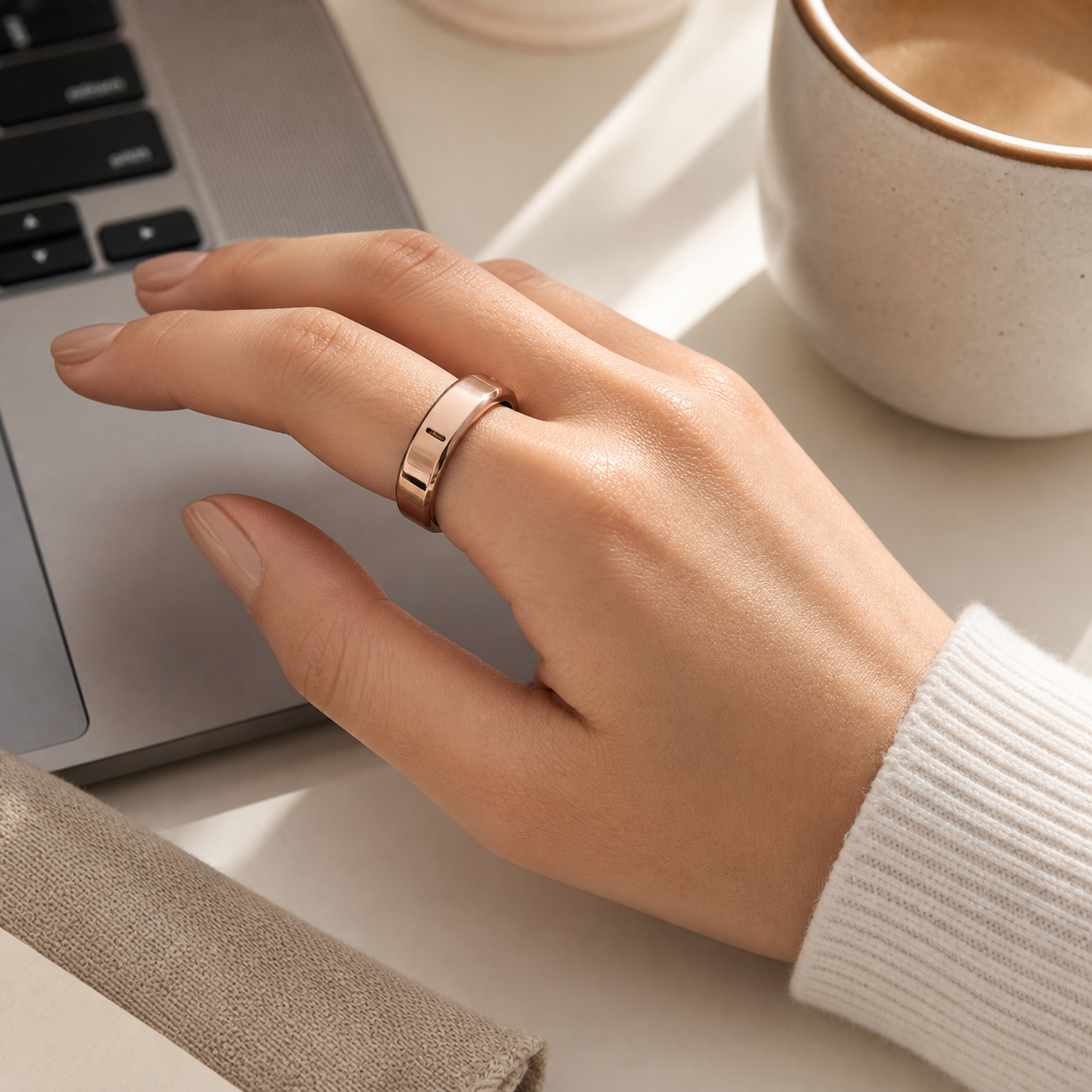 Rose gold metallic TPU Oura Ring cover worn while working at a laptop