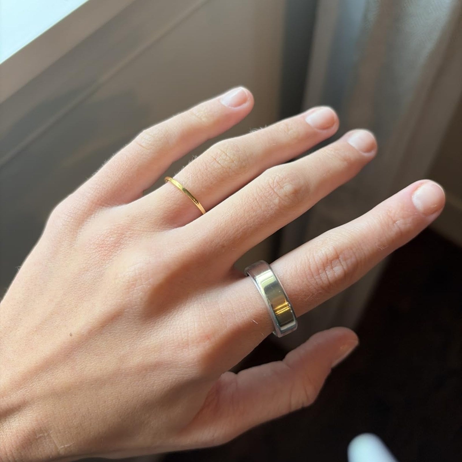 Silver-tone Oura Ring cover photographed on a hand beside a bright window